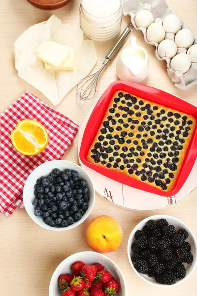 Hornear sabroso pastel e ingredientes para ello en la mesa en la cocina —  Fotos de Stock