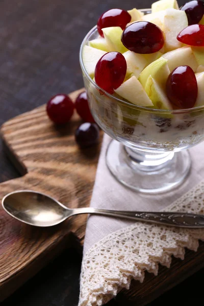 Zdrowe śniadanie - jogurt z musli i świeżych winogron i jabłko kromki serwowane w szklanej misce, na tle drewniane — Zdjęcie stockowe
