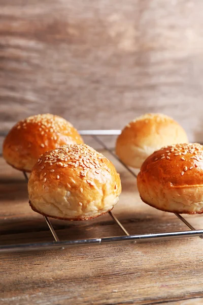 Lekkere broodjes met sesame op oven-tray, op houten achtergrond — Stockfoto