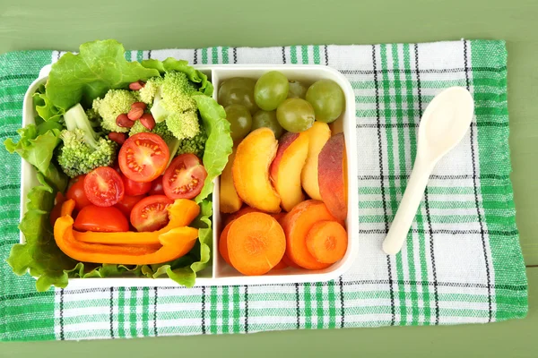 Sabrosa comida vegetariana en caja de plástico sobre mesa de madera verde — Foto de Stock