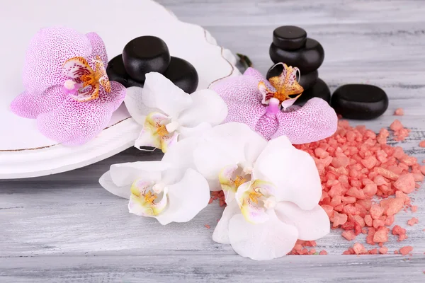 Kleurrijke tropische orchideebloemen en spa stenen op een houten achtergrond kleur — Stockfoto