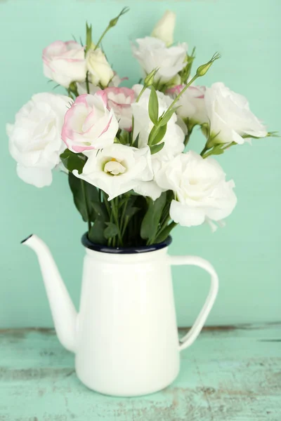 Beautiful eustoma flowers in teapot, on wooden background — Stock Photo, Image