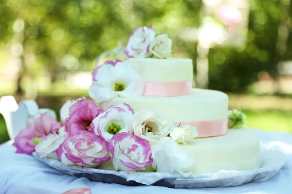 Красивый свадебный торт с цветами на столе, на открытом воздухе — стоковое фото
