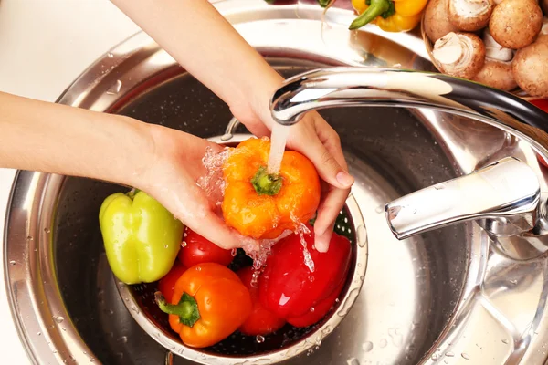 As mãos da mulher que lava verduras na pia na cozinha — Fotografia de Stock