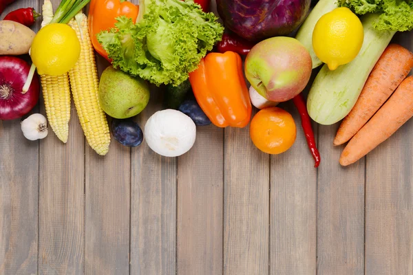 Frutas e legumes orgânicos frescos sobre fundo de madeira — Fotografia de Stock