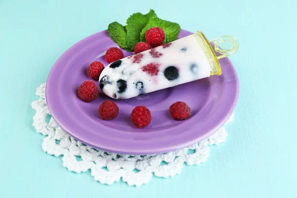 Tasty ice cream pop with fresh berries on plate, on color wooden background — Stock Photo, Image