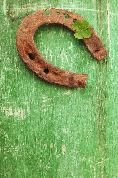 Zapato de caballo viejo, con hoja de trébol, sobre fondo de madera — Foto de Stock