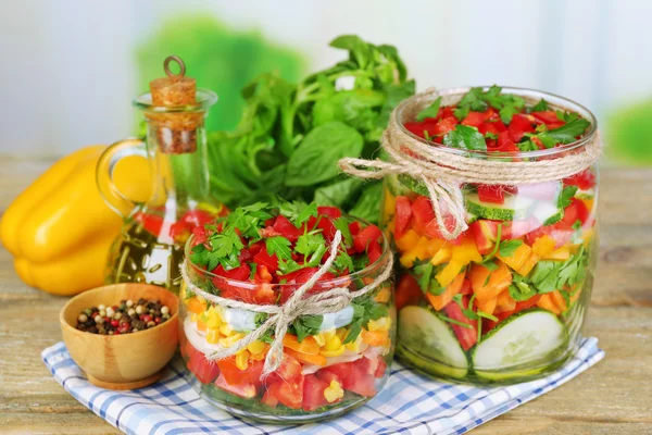 Insalata di verdure in barattoli di vetro su tavolo di legno, su sfondo luminoso — Foto Stock