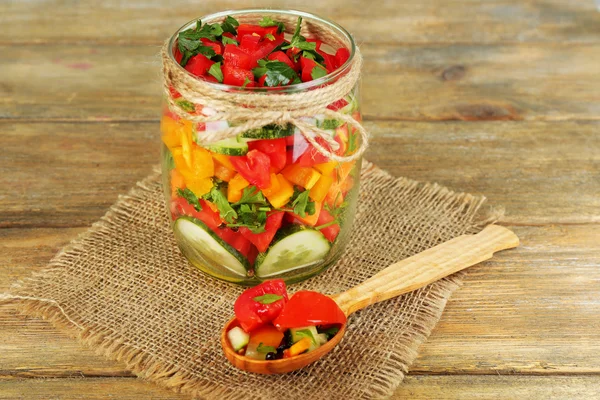 Ensalada de verduras en frasco de vidrio, en servilleta de saco, sobre fondo de madera — Foto de Stock