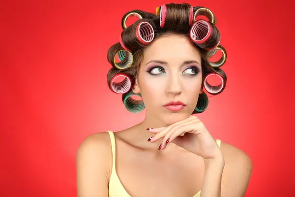 Beautiful girl in hair curlers on red background — Stock Photo, Image
