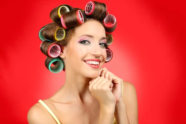 Menina bonita em encrespadores de cabelo no fundo vermelho — Fotografia de Stock