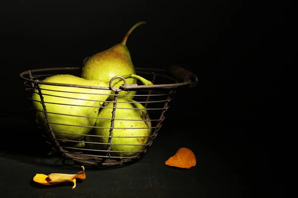 Pêras maduras saborosas em cesta de metal, na mesa, no fundo escuro — Fotografia de Stock