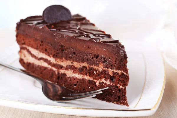 Stück Schokoladenkuchen auf Teller auf Holztisch auf Teekanne Hintergrund — Stockfoto