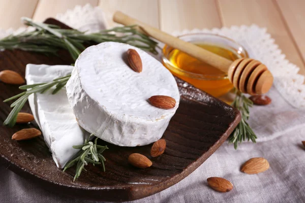 Brie ve Camembert peyniri tabakta bal peçete ahşap arka plan üzerinde cam kase fındık — Stok fotoğraf