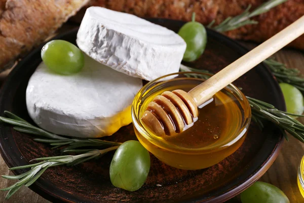 Queijo camembert em prato, mel, uvas, nozes e pão sobre fundo de madeira — Fotografia de Stock