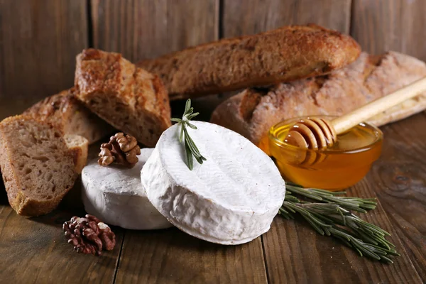 Queijo camembert em prato, mel, nozes e pão sobre fundo de madeira — Fotografia de Stock