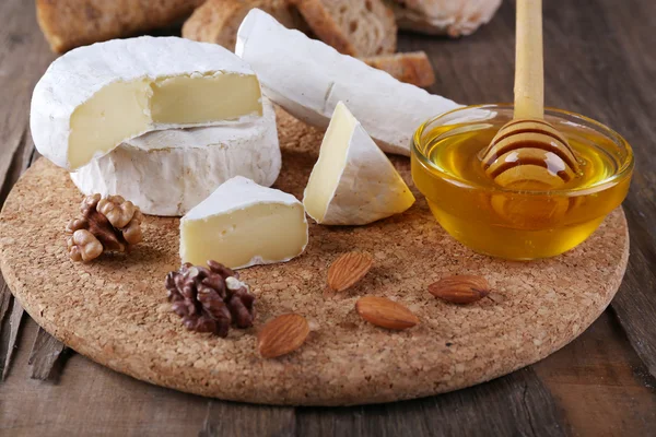 Queijo camembert, nozes, mel e pão sobre tábua de corte sobre fundo de madeira — Fotografia de Stock