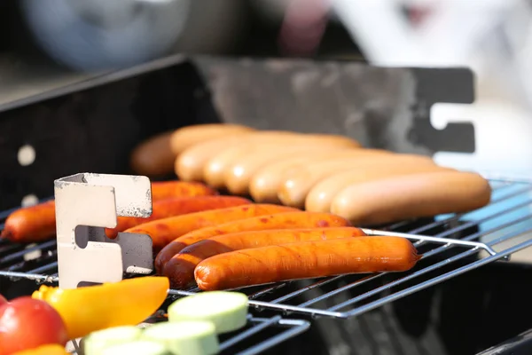 Sausages and vegetables on barbecue grill, close-up — Stock Photo, Image