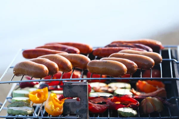 Sausages and vegetables on barbecue grill, outdoors — Stock Photo, Image