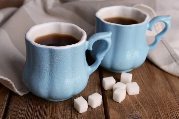 Cups of coffee with sugar and napkin on wooden table — Stock Photo, Image