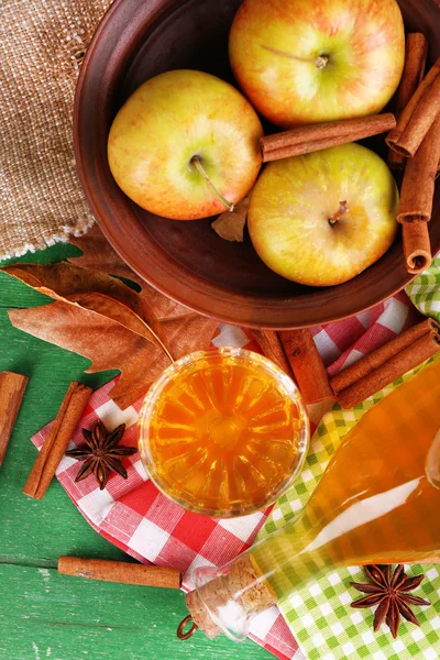 Sammansättningen av äppelcider med kanel pinnar, färska äpplen på trä bakgrund — Stockfoto