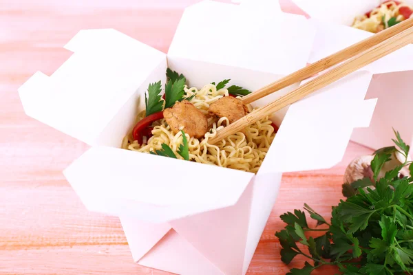 Chinese noodles with meat and pepper in takeaway box on pink background — Stock Photo, Image