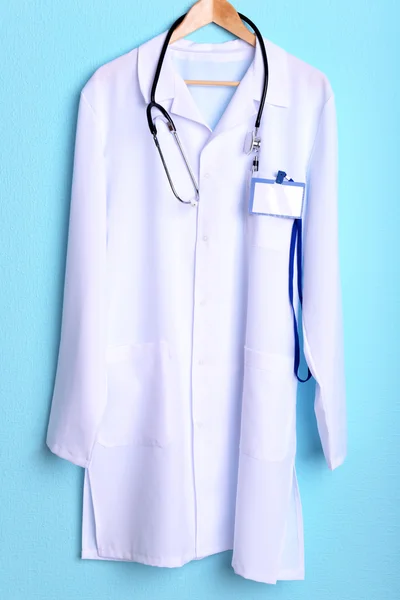 Doktor stetoskop askı üzerinde mavi arka plan üzerinde paltoyla — Stok fotoğraf