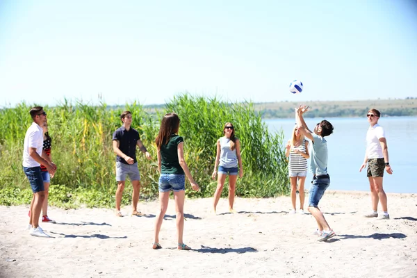 young people playing volleyball on beach