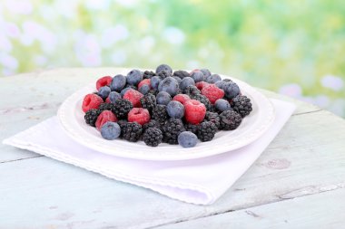 Buzlu meyveleri tabağa parlak arka plan üzerinde renkli ahşap masa üzerinde