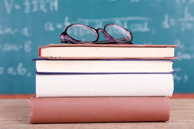 Kitaplar ve gözlükler ahşap masada.