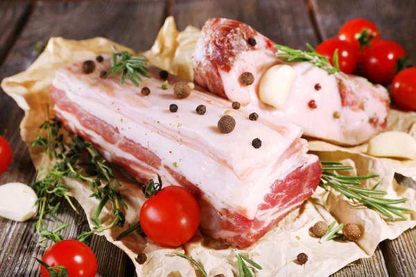 Raw bacon with spices and tomatoes on wooden table — Stock Photo, Image