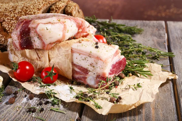 Raw bacon with spices and tomatoes on wooden table — Stock Photo, Image