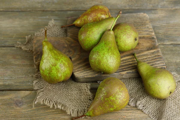 Rijpe peren op snijplank, op houten achtergrond — Stockfoto