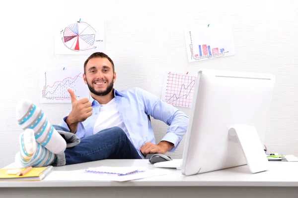 Confident businessman holding his legs in funny socks on desk — Stock Photo, Image