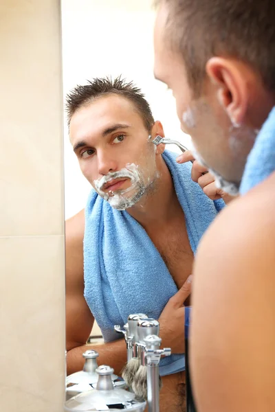 Jeune homme rasant sa barbe dans la salle de bain — Photo