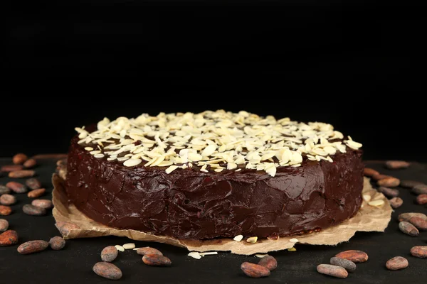 Tasty chocolate cake with almond, on wooden table, on dark background — Stock Photo, Image