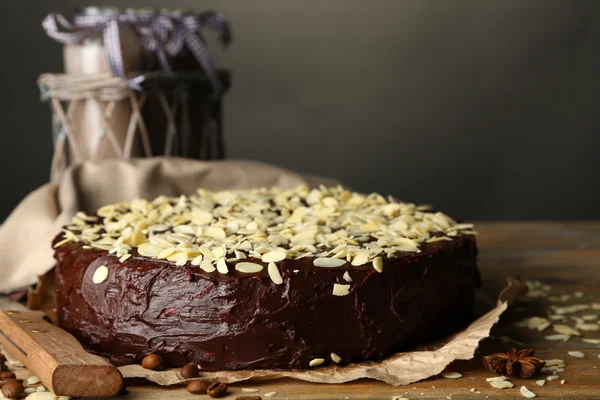 Leckere Schokoladenkuchen mit Mandeln, auf Holztisch, auf dunklem Hintergrund — Stockfoto