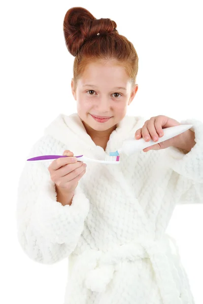 Krásná holčička v županu, zubní kartáček a pastu izolovaných na bílém — Stock fotografie