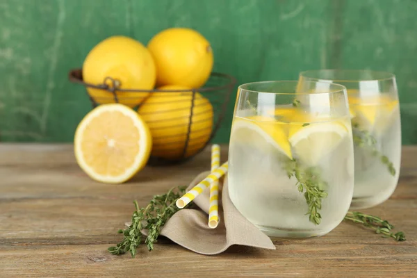 Tasty cool beverage with lemon and thyme, on wooden background — Zdjęcie stockowe