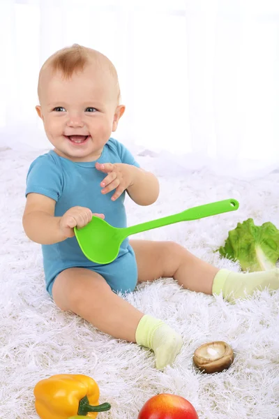 Lindo bebé con frutas y verduras en la alfombra en la habitación — Foto de Stock