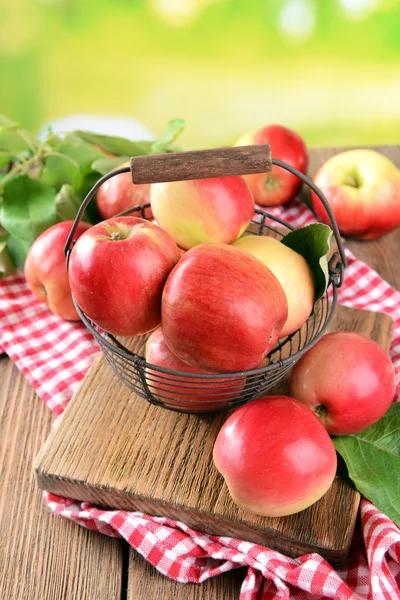 Manzanas dulces en canasta de mimbre sobre mesa sobre fondo brillante — Foto de Stock