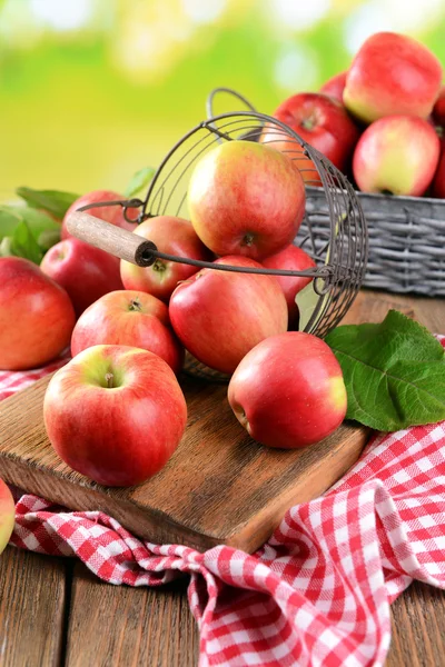 Manzanas dulces en canasta de mimbre sobre mesa sobre fondo brillante — Foto de Stock