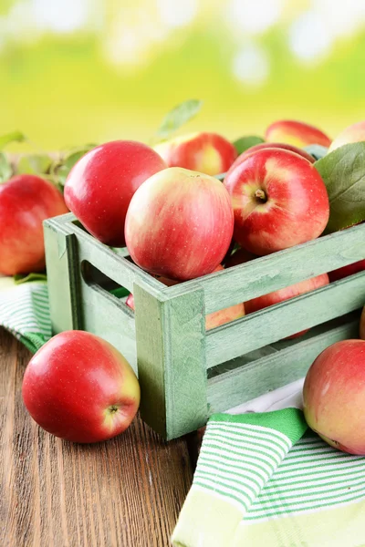 Manzanas dulces en caja de madera sobre mesa sobre fondo brillante — Foto de Stock