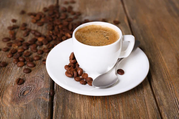 Чашка кофе с молоком и кофейными зёрнами на деревянном фоне — стоковое фото