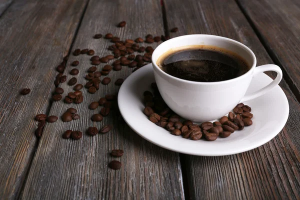 Taza de café y granos de café sobre fondo de madera —  Fotos de Stock