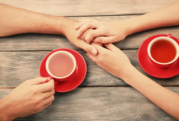 Tazas de té y de la mano en la mesa de madera —  Fotos de Stock