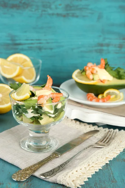 Tasty salads with shrimps and avocado in glass bowl and on plate, on wooden background — Stock Photo, Image
