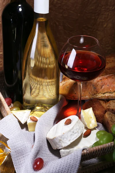 Večeře sestávající z Camembert a brie sýr, med, víno a hrozny na ubrousek v koši na dřevěný stůl na hnědé pozadí — Stock fotografie