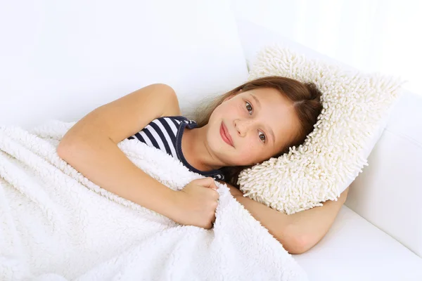 Beautiful little girl lying on sofa in room — Stock Photo, Image