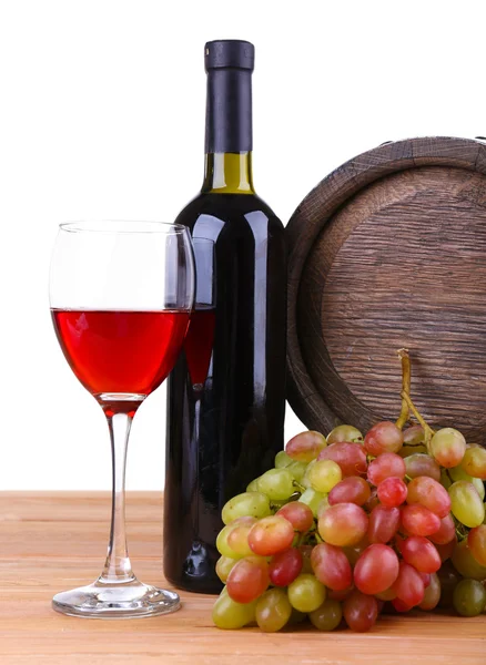 Wine in goblet and in bottle, grapes and barrel on wooden table on white background — Stock Photo, Image